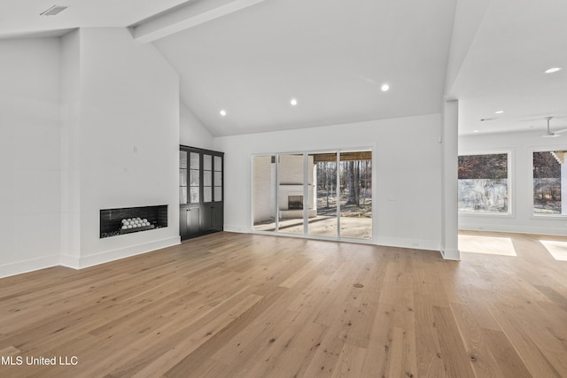 unfurnished living room featuring plenty of natural light, light wood-type flooring, beamed ceiling, and a fireplace