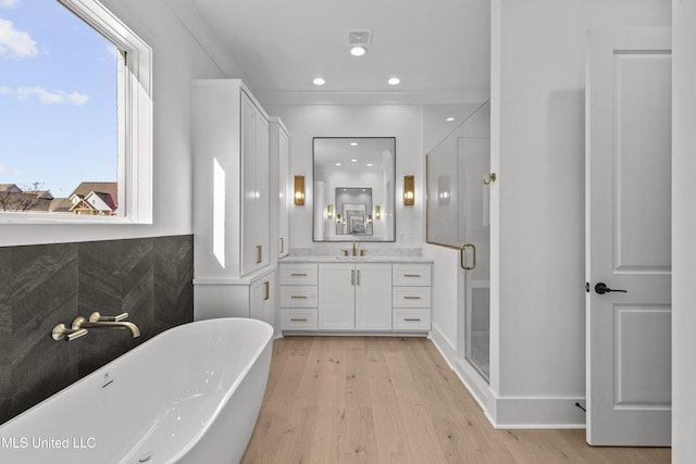 full bathroom featuring a stall shower, a soaking tub, wood finished floors, and vanity