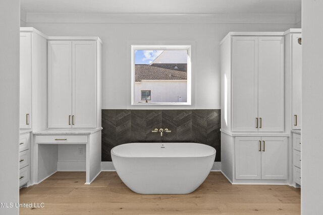 full bathroom with a closet, wainscoting, a soaking tub, and wood finished floors