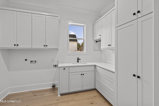 laundry room with washer hookup, a sink, cabinet space, light wood finished floors, and electric dryer hookup