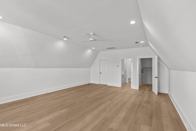 additional living space with lofted ceiling, visible vents, light wood-style flooring, a ceiling fan, and baseboards