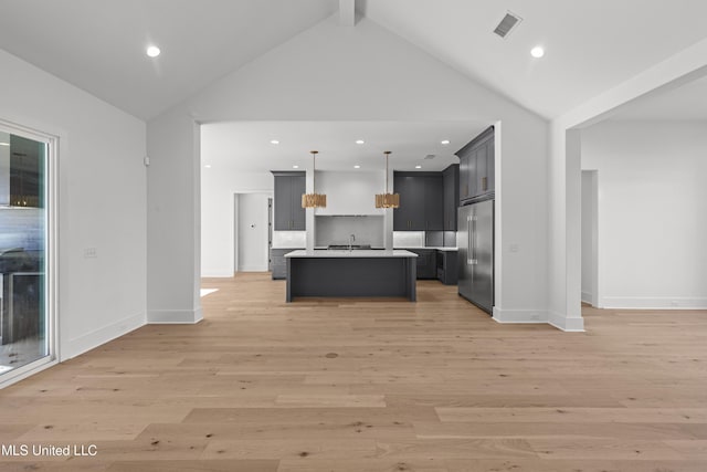 kitchen featuring a center island with sink, light countertops, hanging light fixtures, open floor plan, and stainless steel built in refrigerator