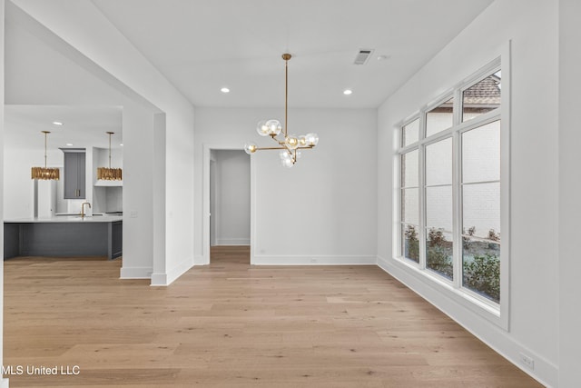 unfurnished dining area featuring light wood-type flooring, a wealth of natural light, visible vents, and a notable chandelier