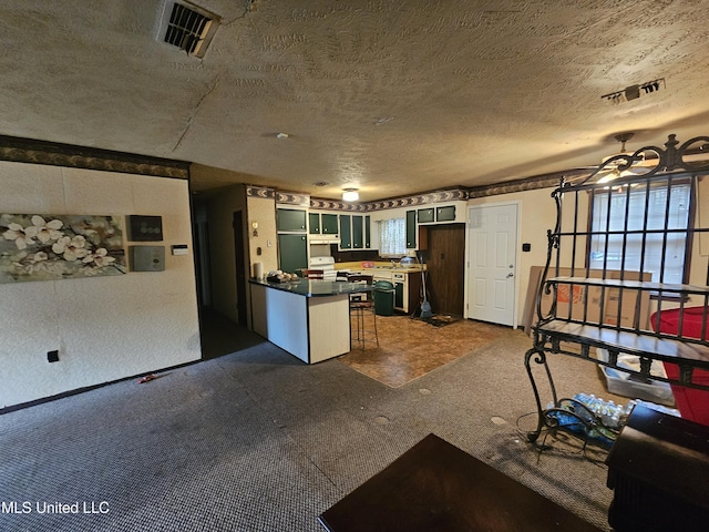 kitchen featuring dark countertops, visible vents, white cabinetry, a textured ceiling, and a kitchen bar