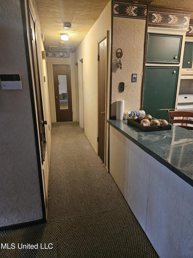 hall featuring carpet and a textured ceiling