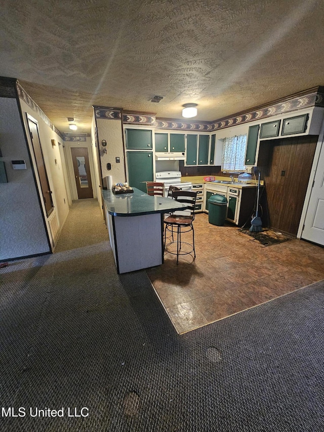 kitchen with a textured ceiling, carpet flooring, visible vents, and a kitchen breakfast bar