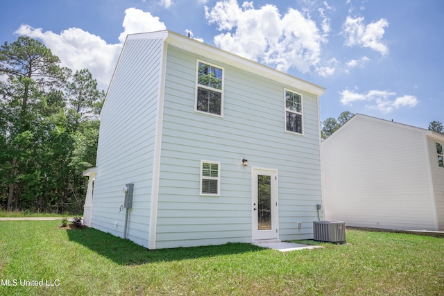 rear view of house with central AC and a lawn