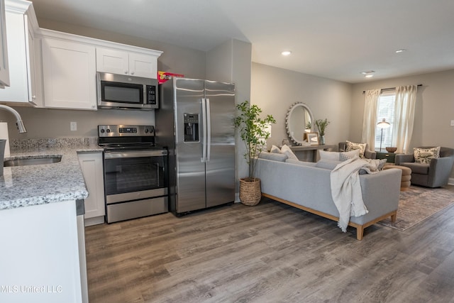 kitchen featuring sink, white cabinetry, light stone counters, appliances with stainless steel finishes, and hardwood / wood-style flooring