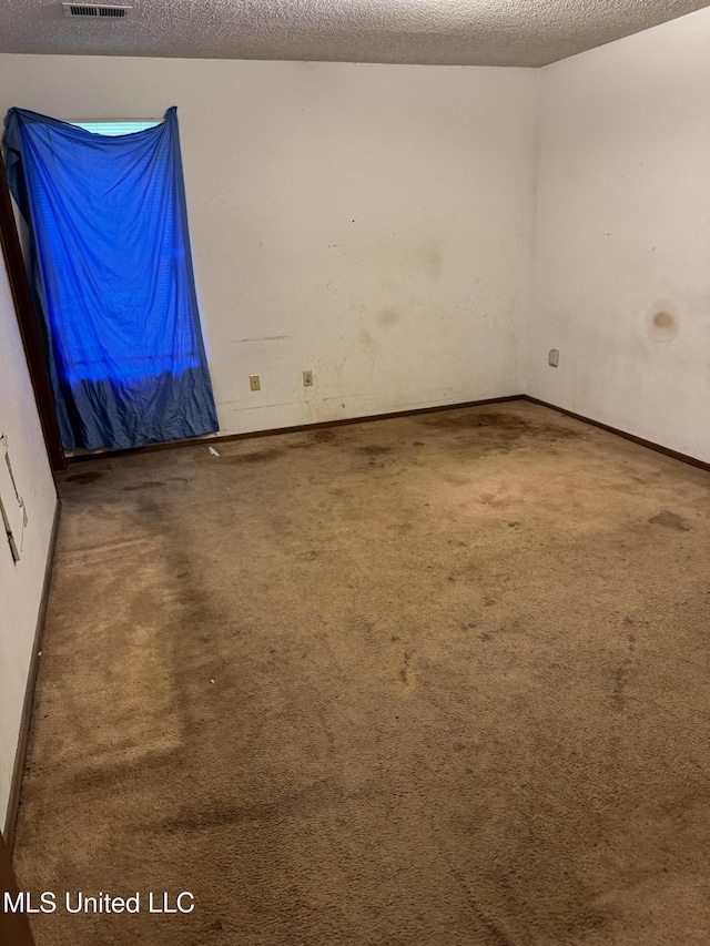 unfurnished room featuring carpet floors, a textured ceiling, and baseboards