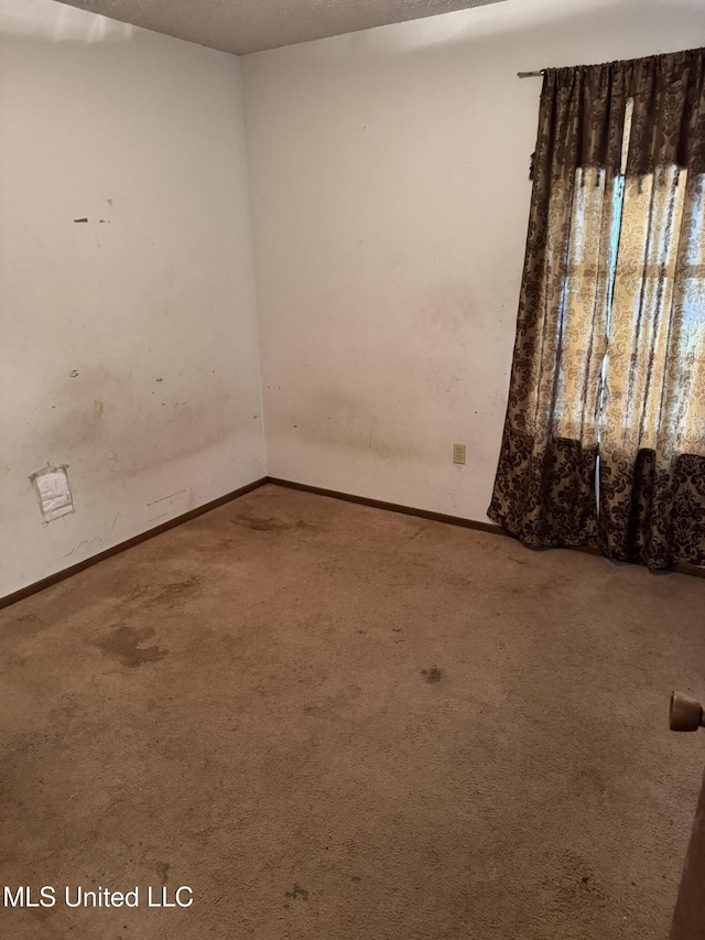 unfurnished room with carpet flooring and baseboards
