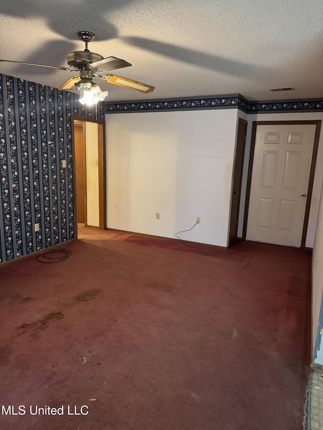 spare room featuring a ceiling fan, carpet floors, a textured ceiling, and wallpapered walls
