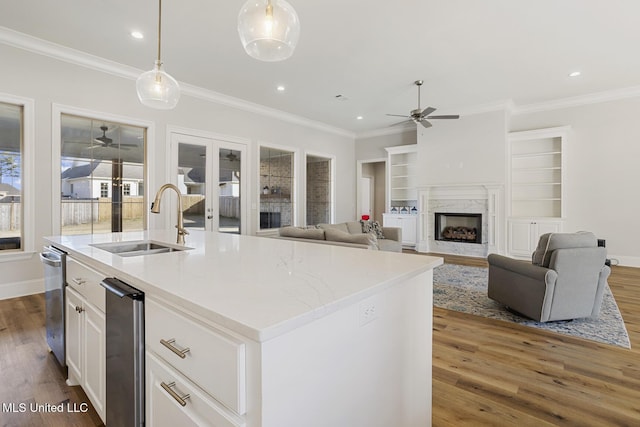 kitchen with pendant lighting, a premium fireplace, open floor plan, a sink, and an island with sink