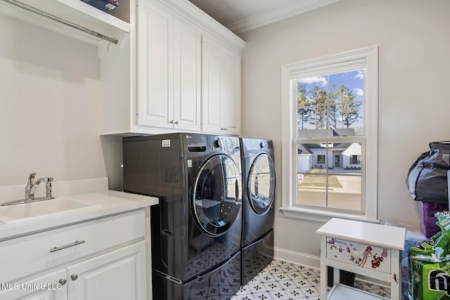 laundry area with crown molding, cabinet space, a sink, washer and dryer, and baseboards