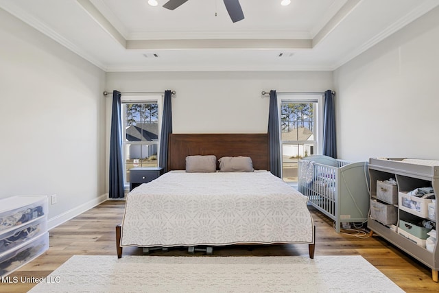 bedroom featuring crown molding, wood finished floors, a raised ceiling, and baseboards