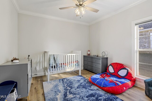 bedroom featuring baseboards, light wood finished floors, a ceiling fan, and crown molding