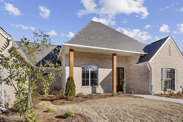 view of front of property featuring a shingled roof and brick siding