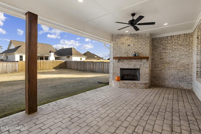 view of patio featuring an outdoor brick fireplace, a fenced backyard, and a ceiling fan