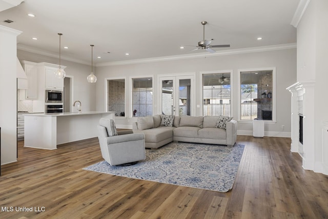 living room featuring recessed lighting, dark wood-type flooring, a fireplace, baseboards, and ornamental molding