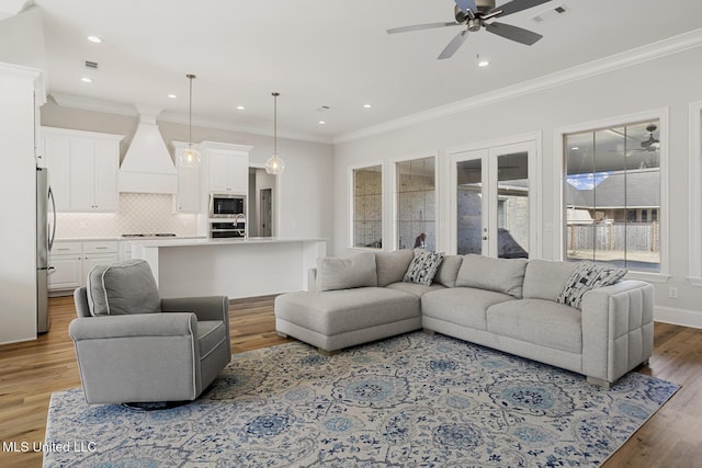 living area featuring recessed lighting, light wood-type flooring, visible vents, and crown molding