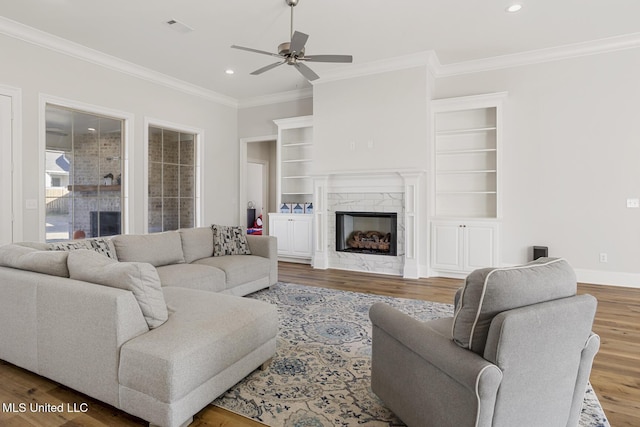 living room featuring recessed lighting, visible vents, a premium fireplace, wood finished floors, and baseboards