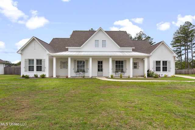 view of front of property with a front yard, a porch, metal roof, fence, and a standing seam roof