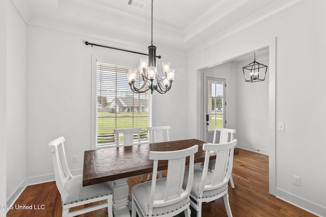 dining space with visible vents, an inviting chandelier, and wood finished floors
