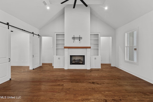unfurnished living room featuring dark wood-style flooring, baseboards, a fireplace, a barn door, and ceiling fan