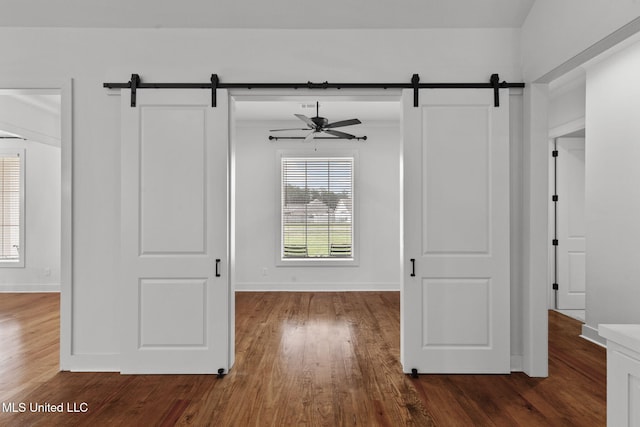 interior space with a barn door, dark wood-style flooring, and baseboards