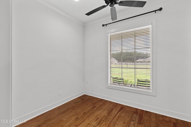 unfurnished room featuring crown molding, baseboards, a ceiling fan, and dark wood-style floors