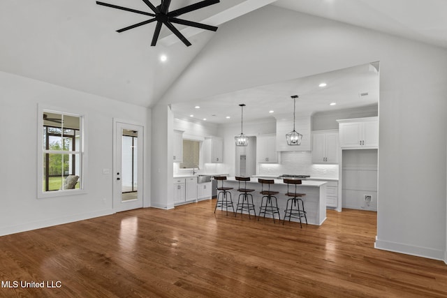 kitchen featuring wood finished floors, ceiling fan, white cabinets, and a kitchen breakfast bar