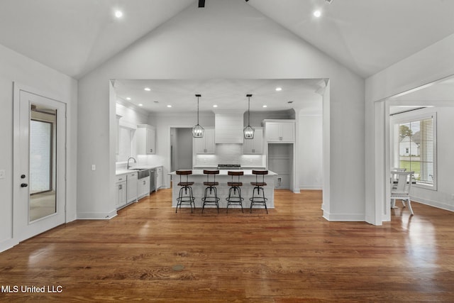 kitchen with a breakfast bar area, wood finished floors, a sink, and white cabinets