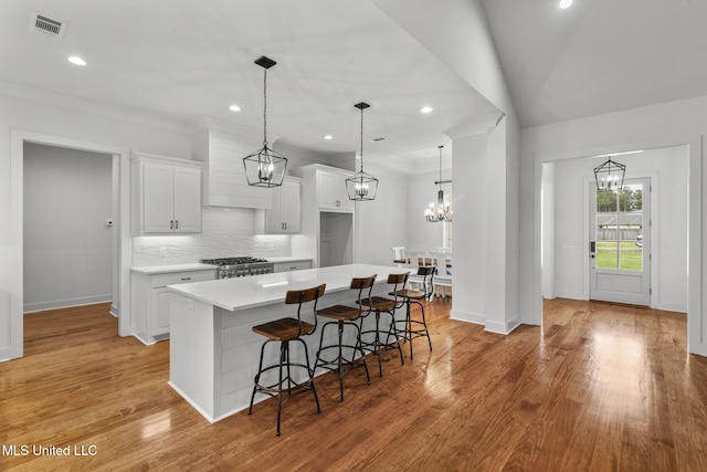 kitchen featuring white cabinets, light countertops, decorative backsplash, range, and a kitchen island