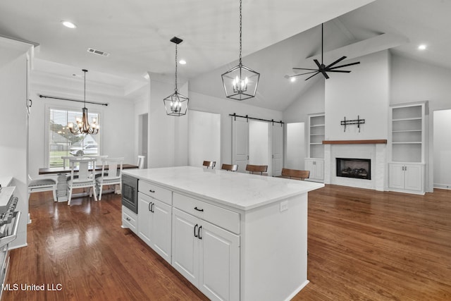 kitchen featuring stainless steel microwave, a barn door, visible vents, and dark wood finished floors