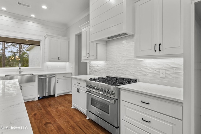 kitchen with premium range hood, white cabinetry, visible vents, stainless steel appliances, and a sink