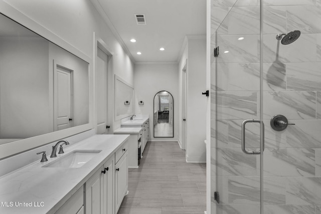 full bathroom with two vanities, a stall shower, crown molding, visible vents, and a sink