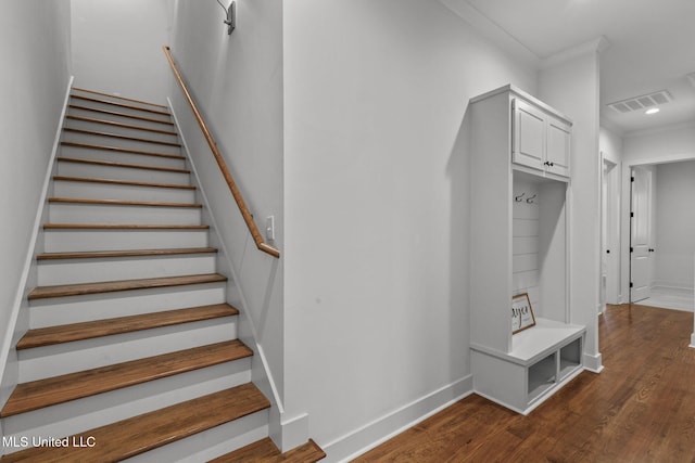 staircase featuring visible vents, baseboards, crown molding, and wood finished floors