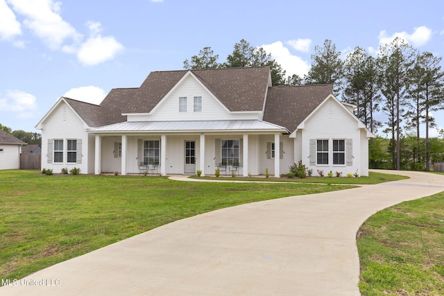 modern farmhouse style home with covered porch, metal roof, a standing seam roof, and a front lawn