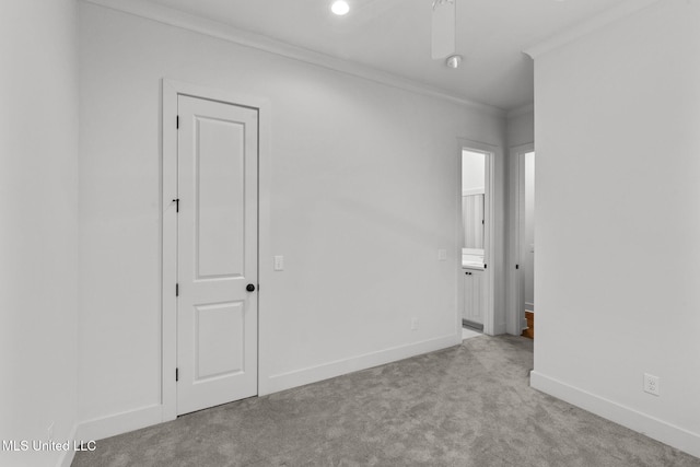 carpeted spare room with baseboards, ornamental molding, and a ceiling fan