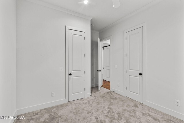 unfurnished bedroom featuring crown molding, baseboards, two closets, and carpet
