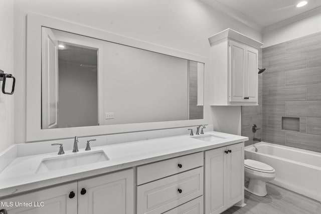 bathroom with double vanity, shower / bathtub combination, a sink, and toilet
