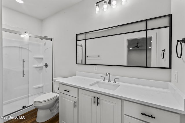 full bathroom featuring toilet, a stall shower, wood finished floors, and vanity