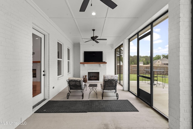 sunroom featuring brick wall, a fireplace, and a ceiling fan