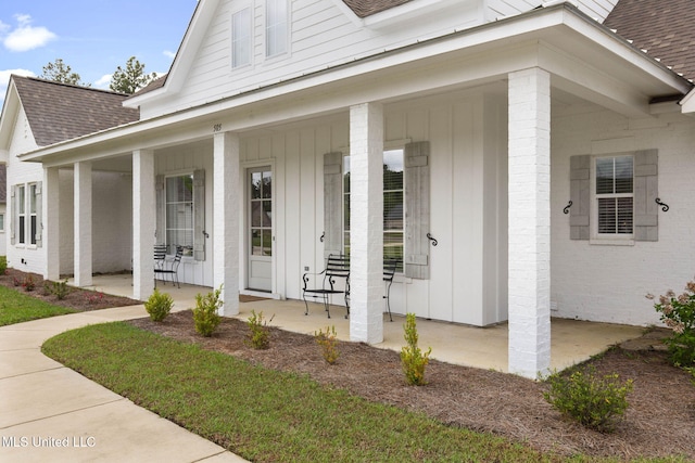 view of exterior entry with a porch and roof with shingles