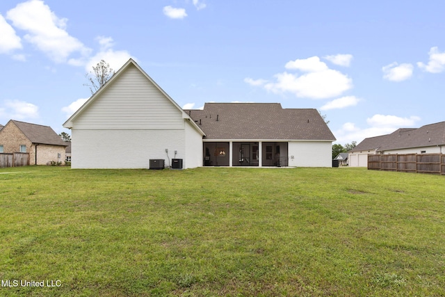 rear view of property with fence, a yard, central AC unit, and a sunroom