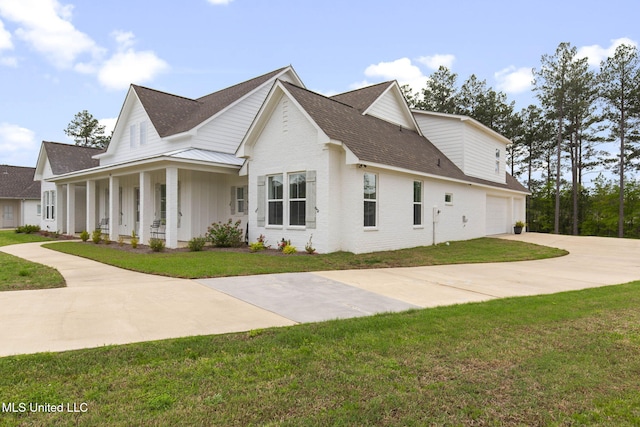 view of side of property with roof with shingles, driveway, an attached garage, a porch, and a lawn