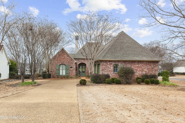 view of front of house featuring brick siding, driveway, and a shingled roof