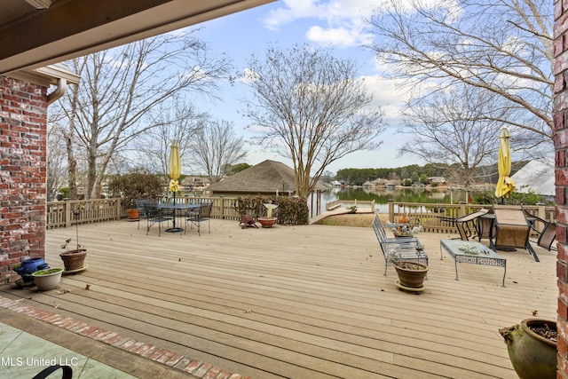 deck with outdoor dining space and a water view