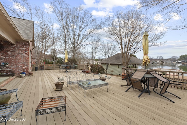 wooden deck with outdoor dining area and a water view