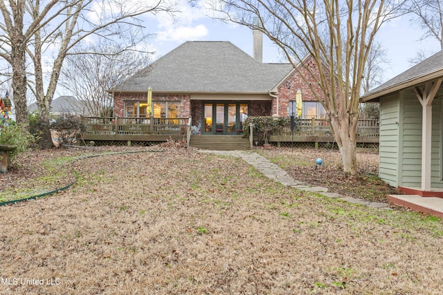 back of house featuring brick siding, a chimney, and a wooden deck