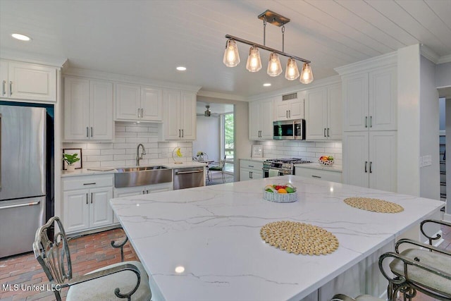 1844 Eastover Dr, Jackson, MS 39211 - kitchen with a breakfast bar, a sink, brick floor, stainless steel appliances, and white cabinetry